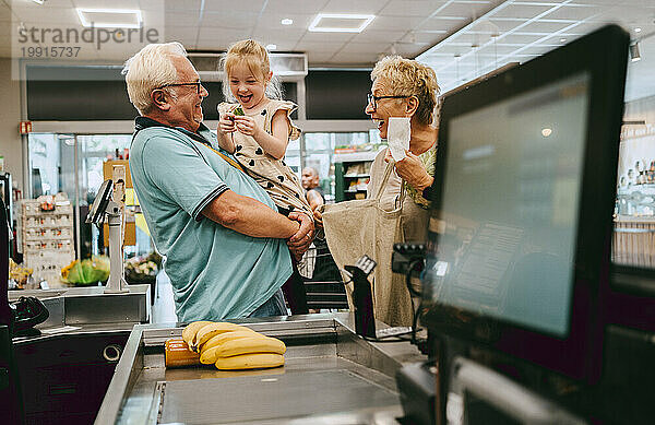 Glückliche Enkelin  die Spaß mit Großeltern beim Einkaufen im Supermarkt hat