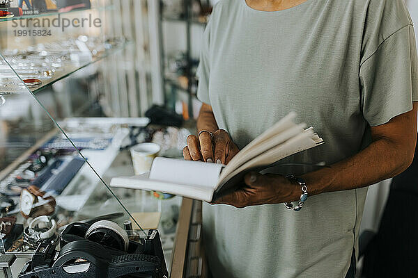 Mittelteil einer Verkäuferin mit Tagebuch  die im Antiquitätengeschäft steht