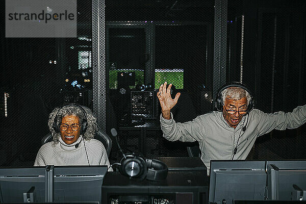 Überraschter älterer Mann besiegt Freundin beim Videospiel im Gaming-Center