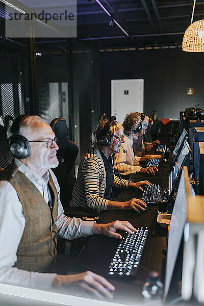 Ältere männliche und weibliche Freunde spielen Videospiele auf Computern in der Gaming-Lounge