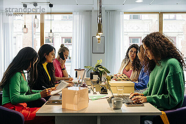 Gemischtrassige Unternehmerinnen arbeiten zusammen  während sie im Büro am Schreibtisch sitzen