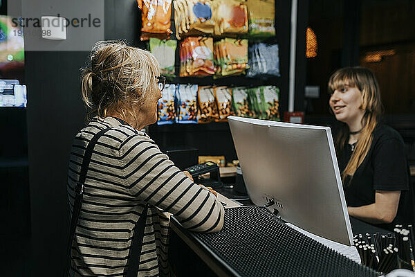Ältere Frau im Gespräch mit Verkäuferin in der Gaming-Lounge