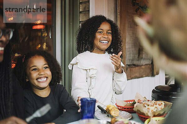 Glückliche Geschwister lachen mit Essen und Snacks auf dem Tisch im Restaurant