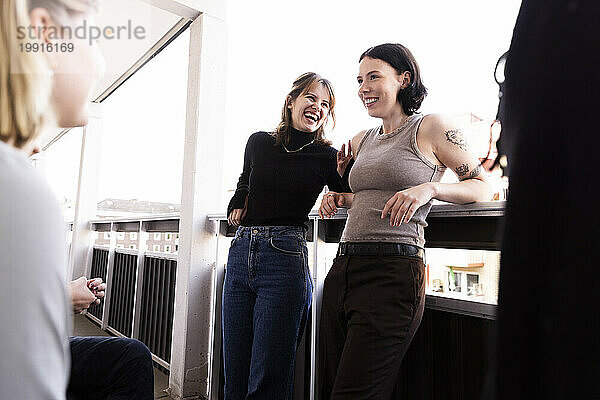 Fröhliche junge Freundinnen lachen und haben Spaß auf dem Balkon