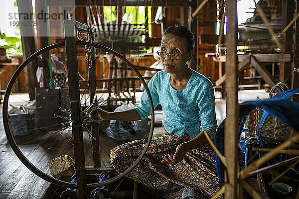 Ältere Frau webt Seide auf einem Spinnrad im Haus  Shan State  Myanmar