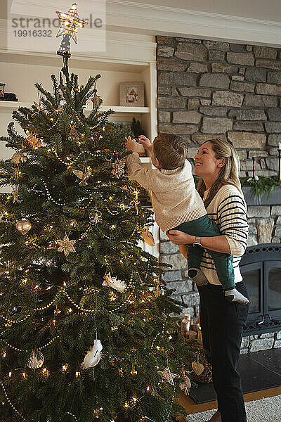 Mutter und Kleinkind schmücken fröhlich den ästhetischen Weihnachtsbaum