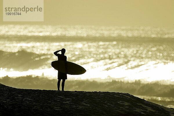 Silhouette eines Surfers mit rollenden Wellen im Hintergrund