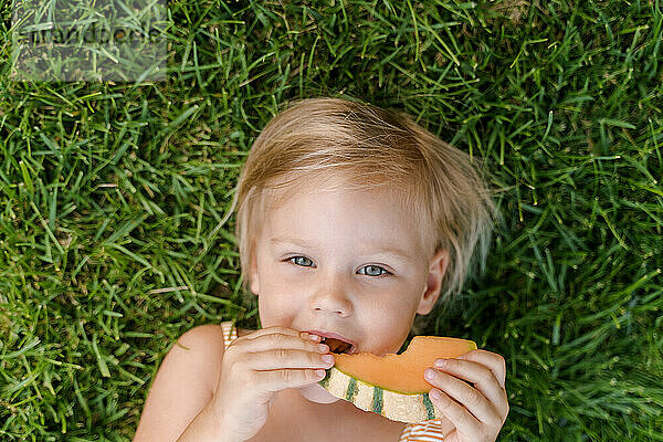Zeit  Obst zu essen  süßes Mädchen isst Melone  während es im Gras liegt
