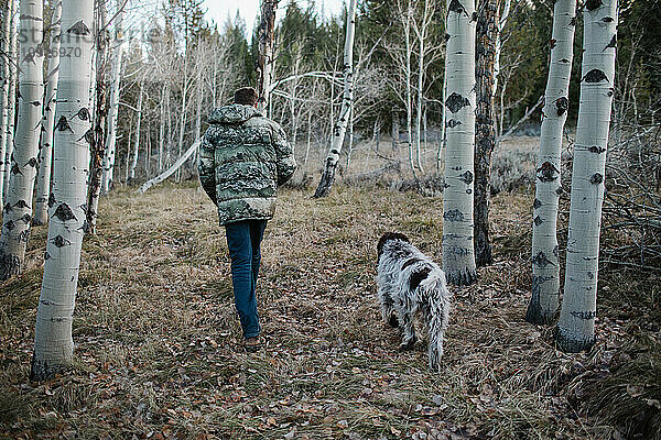 Mann mit Hund läuft durch einen ruhigen Espenwald in Idaho
