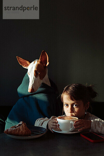 Kindermädchen mit Hundefreund im Café  Kaffee  Croissants  Freundschaft.