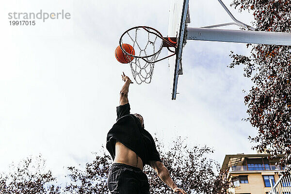 Multiethnischer Junge schießt Korb und spielt Basketball