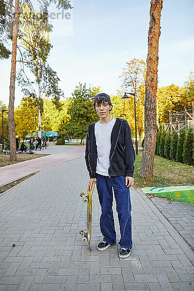 Junger Mann mit Skateboard im Park