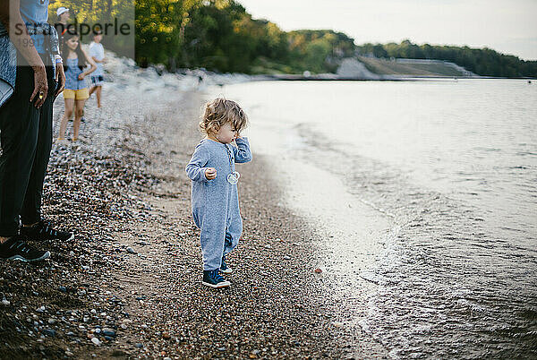 Kleinkind wirft mit Familie Steine ??in See am felsigen Strand