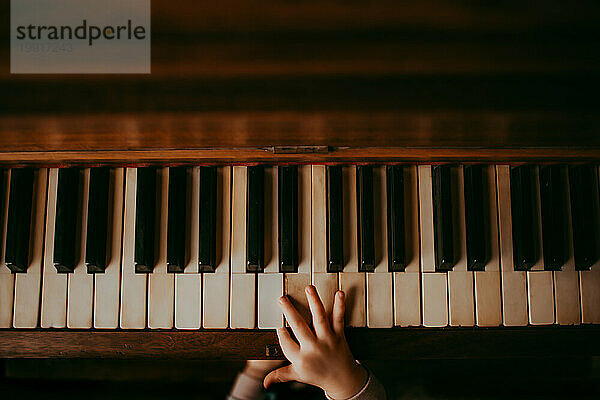 Die Hände eines Kindes spielen auf einem alten Klavier