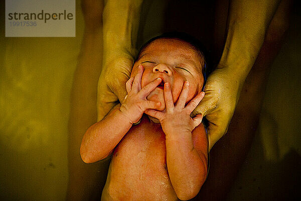 Ein neugeborener Junge nimmt mit seiner Mutter ein Kräuterbad.