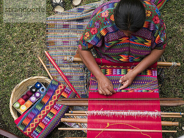 Eine Frau aus einer indigenen Gemeinschaft in Guatemala webt  während sie bei der Arbeit in Antigua  Guatemala  ein indigenes Kleid trägt.