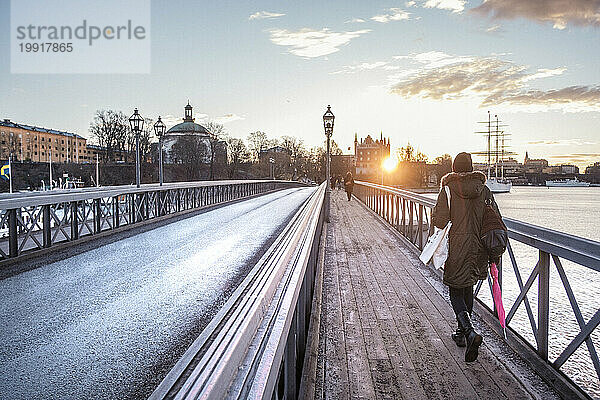 Menschen  die bei Sonnenuntergang über die Brücke über den Fluss gehen  Stockholm  Schweden