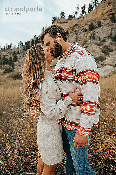 Mama und Papa teilen einen romantischen Kuss in der Natur