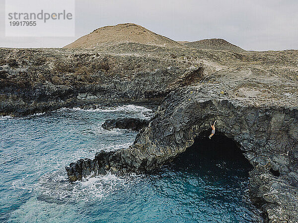 Mann klettert in einer Höhle am Meer  Teneriffa  Kanarische Inseln  Spanien