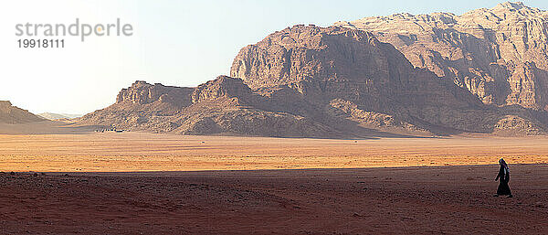 Panorama eines Mannes in Schwarz  der in der Wüste  Wadi Rum  spaziert