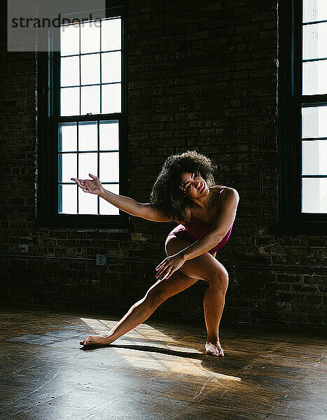 Frau gemischter Abstammung tanzt zeitgenössische Pose mit Fensterlicht