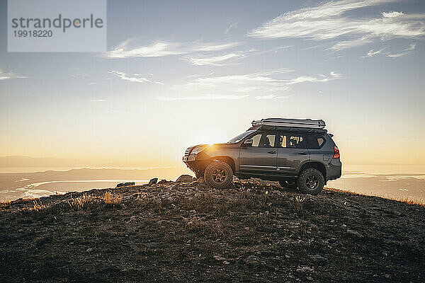 Graues 4x4-Fahrzeug bei Sonnenuntergang auf einem Berg geparkt