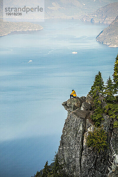 Aktiver Mann sitzt auf einer Klippe mit atemberaubender Aussicht in der Nähe von Vancouver.