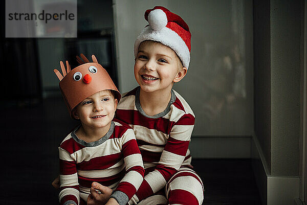 Nahaufnahme von zwei kleinen Jungen  die lächeln und einen Weihnachtspyjama tragen