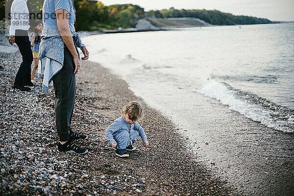 Kleinkind sammelt Steine ??am Strand des Sees mit der Familie