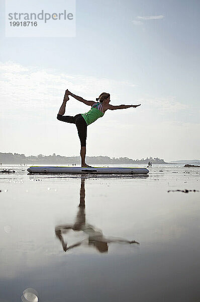 Eine Frau praktiziert Yoga an einem Strand im Süden von Maine.
