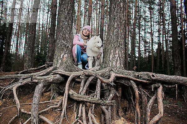 Junges Mädchen geht mit einem weißen  flauschigen Samojedenhund in der Natur spazieren