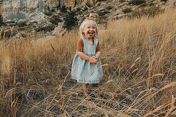 2-jähriges Mädchen steht draußen und lacht vor Freude