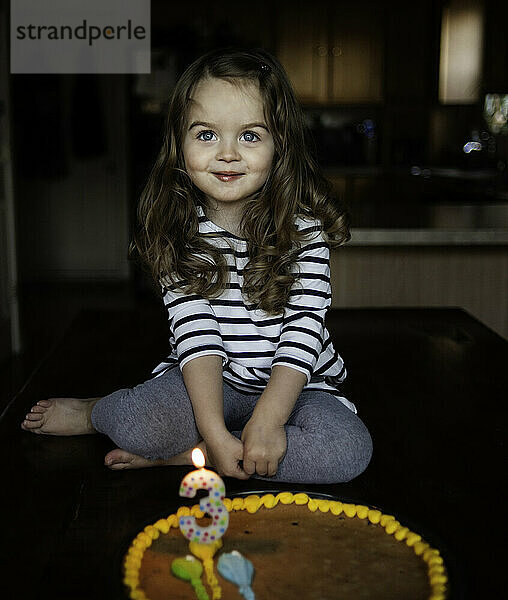 Glückliches kleines Mädchen  das mit Geburtstagstorte lächelt