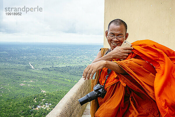 Buddhistischer Mönch lächelt  nachdem er Fotos vom Gipfel des Mount Popa  Myanmar  gemacht hat