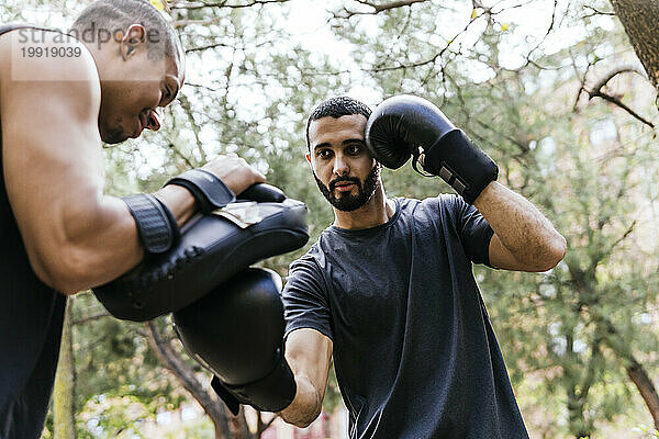 Mann übt mit seinem Trainer Ringen mit Handschuhen und Schutzvorrichtungen