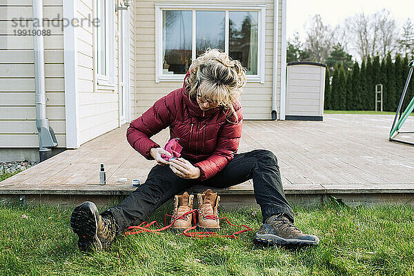Frau putzt draußen zu Hause ihre Wanderschuhe