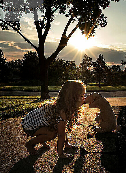 Nettes kleines Mädchen küsst Stoffkaninchen im Freien