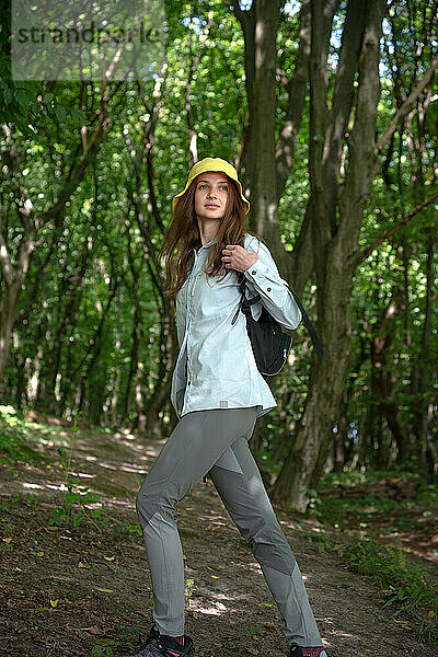 Fröhliche junge Frau  die an einem sonnigen Tag in einem Wald spaziert  Ukraine