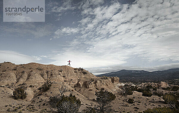 Eine Frau springt in einer dramatischen Landschaft in New Mexico in die Luft.
