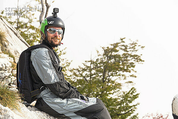 Männlicher Basejumper entspannt sich vor dem Sprung auf Felsen  Brento  Venetien  Italien