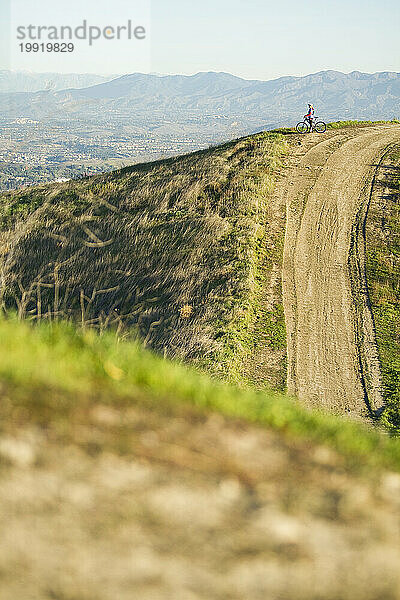 Eine aktive Frau Mitte Zwanzig fährt bei Sonnenaufgang in Südkalifornien mit dem Mountainbike.