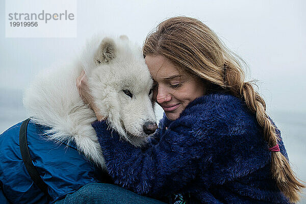 Mädchen geht mit einem weißen  flauschigen Samojedenhund in der Natur spazieren