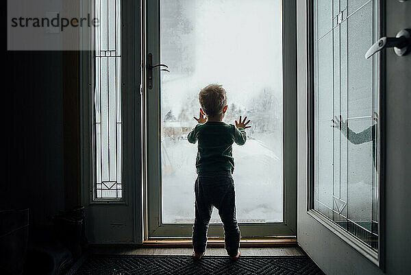 Rückansicht der Silhouette eines kleinen Jungen  der die Hände gegen die Vorderseite drückt