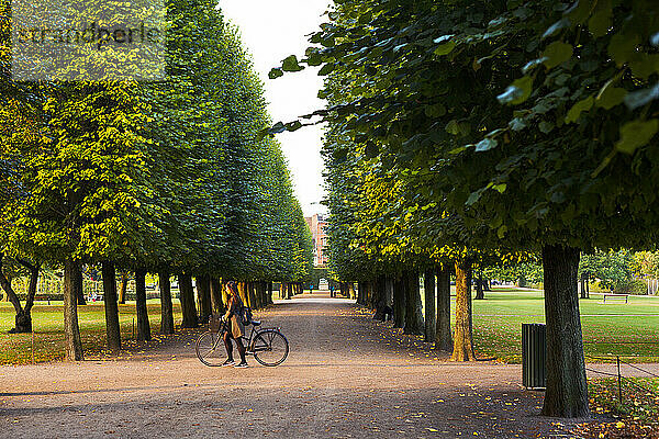 Frau läuft mit ihrem Fahrrad durch Kongens Have (Königsgarten) in Kopenhagen  Dänemark