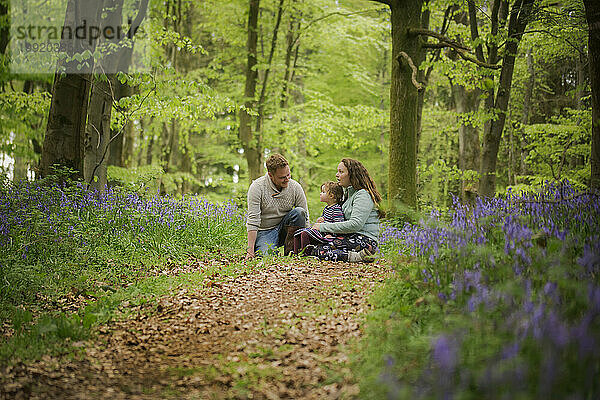 Ein Mann  ein junges Mädchen und Frauen in einem Glockenblumenwald