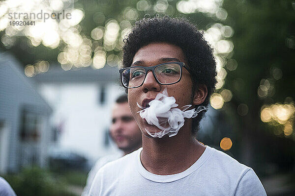 Junger Mann dampft und atmet Rauch aus