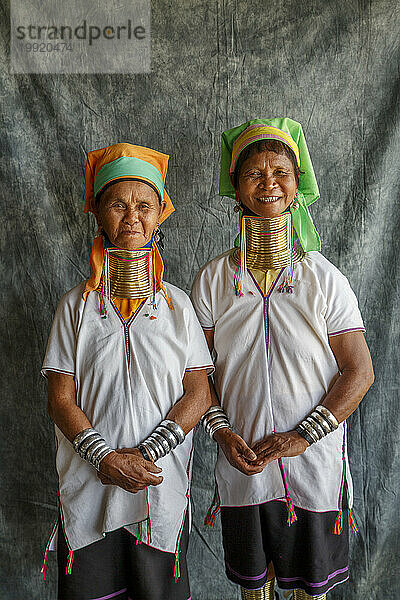 Porträt zweier erwachsener Frauen mit traditionellen Halsringen  die gemeinsam vor grauem Stoff posieren  Shan State  Myanmar