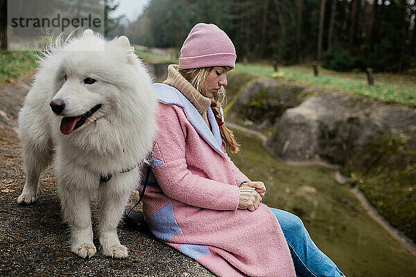 Mädchen geht mit einem weißen  flauschigen Samojedenhund in der Natur spazieren