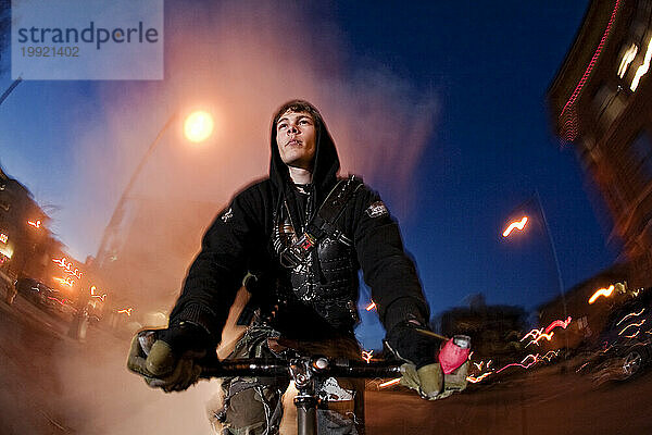 Der Fixed Gear Rider fährt nachts im Kapuzenpullover.