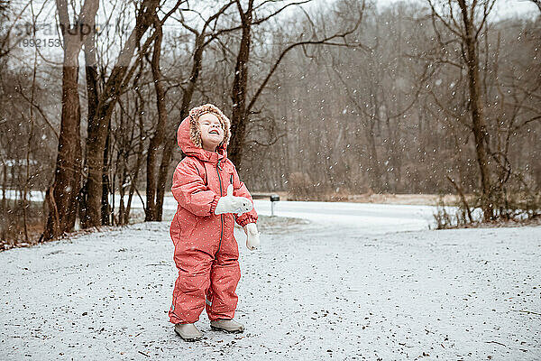Lächelndes Kind  das an einem Wintertag in den Schneefall blickt